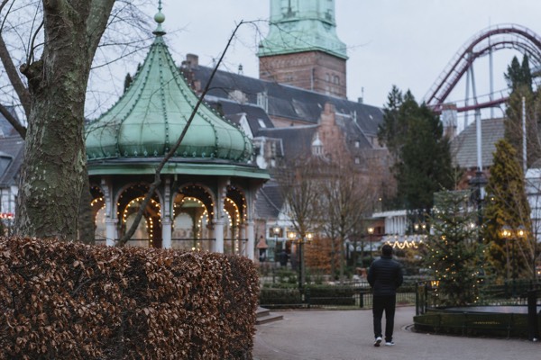 Families walking the lamplit garden paths of Tivoli Gardens in Copenhagen at dusk