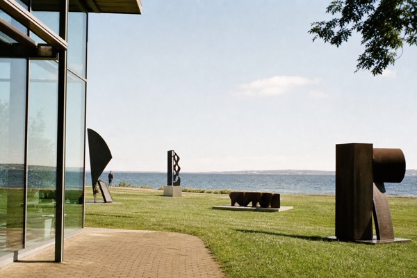 Glass gallery corridor at Louisiana opening onto sculptures and the sea